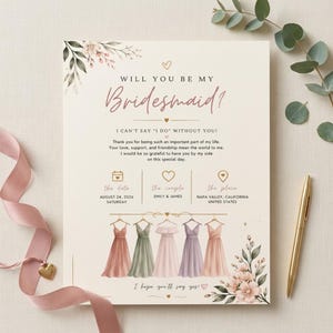 Może przedstawiać: Kremowa karta z napisem Will You Be My Bridesmaid? oraz I Can't Say I Do Without You. Zawiera ilustracje pięciu sukienek na wieszakach w odcieniach różu, zieleni i fioletu, ozdobione motywami kwiatowymi oraz złotymi sercami.