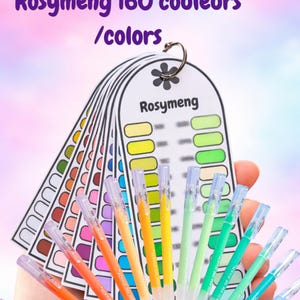 Puede incluir: Un conjunto de bolígrafos de gel acrílico de colores con una carta de colores. Los bolígrafos son de varios tonos de naranja, amarillo, verde y azul. La carta de colores muestra 160 colores y está etiquetada como "Rosymeng". Los bolígrafos están unidos por un anillo de metal.