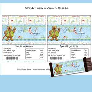 May include: A printable Hershey's chocolate bar wrapper featuring a cartoon bear fishing with the text "Hooked on you". The wrapper is designed for Father's Day and has a blue and white color scheme.