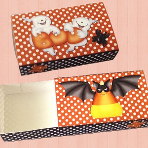May include: A Halloween-themed gift box with a white background and orange polka dots. The top of the box features two ghosts holding a pumpkin and a spider. The bottom of the box features a bat holding a candy corn.