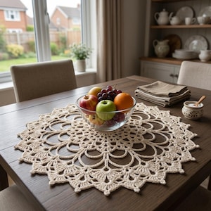 Peut inclure: Nappe en crochet beige sur une table en bois foncé, avec un bol en verre rempli de fruits. Les fruits comprennent des pommes rouges et vertes, des raisins et une orange. Un petit bol en céramique et des serviettes pliées sont également sur la table.