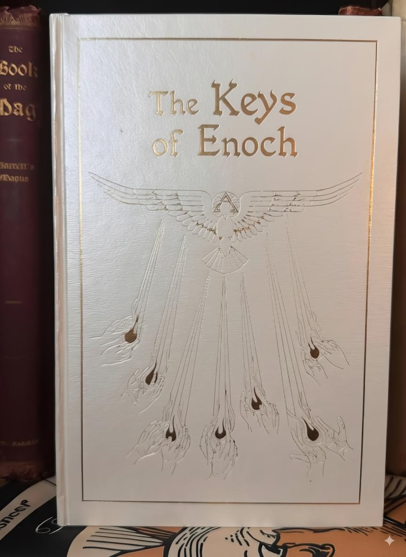 May include: A hardcover book titled "The Keys of Enoch" with gold lettering and embossed illustrations. The cover is white with a gold border and features a dove with outstretched wings and rays emanating from it.