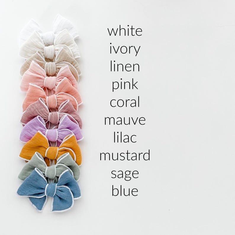 May include: Ten fabric hair bows in various colors, including white, ivory, linen, pink, coral, mauve, lilac, mustard, sage, and blue. Each bow has a white trim.