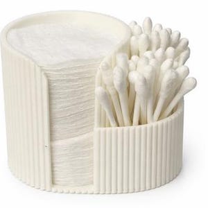 Può includere: Un contenitore color crema a due scomparti contiene una pila di dischetti di cotone rotondi e una collezione di cotton fioc. Il contenitore ha un esterno a coste e un design curvo, offrendo una soluzione di archiviazione ordinata per articoli per la cura della persona.