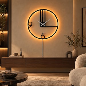 May include: A circular black metal wall clock featuring a minimalist open frame design with the numbers 9 and 6 displayed. The clock includes thin silver hands and integrated warm LED backlighting that casts a soft glow against the wall.