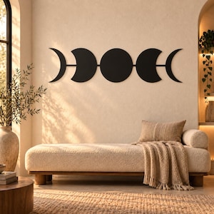 May include: A matte black metal wall art piece featuring a horizontal sequence of five moon phases, including a crescent, a waxing gibbous, a full moon, a waning gibbous, and a crescent, all connected by thin horizontal lines in a linear arrangement.