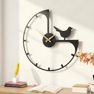Puede incluir: Un reloj de pared con un marco circular negro incompleto y la silueta de un pájaro posado en el lado derecho. El reloj tiene un soporte central circular negro con manecillas doradas para las horas y los minutos, y marcas de hora negras.