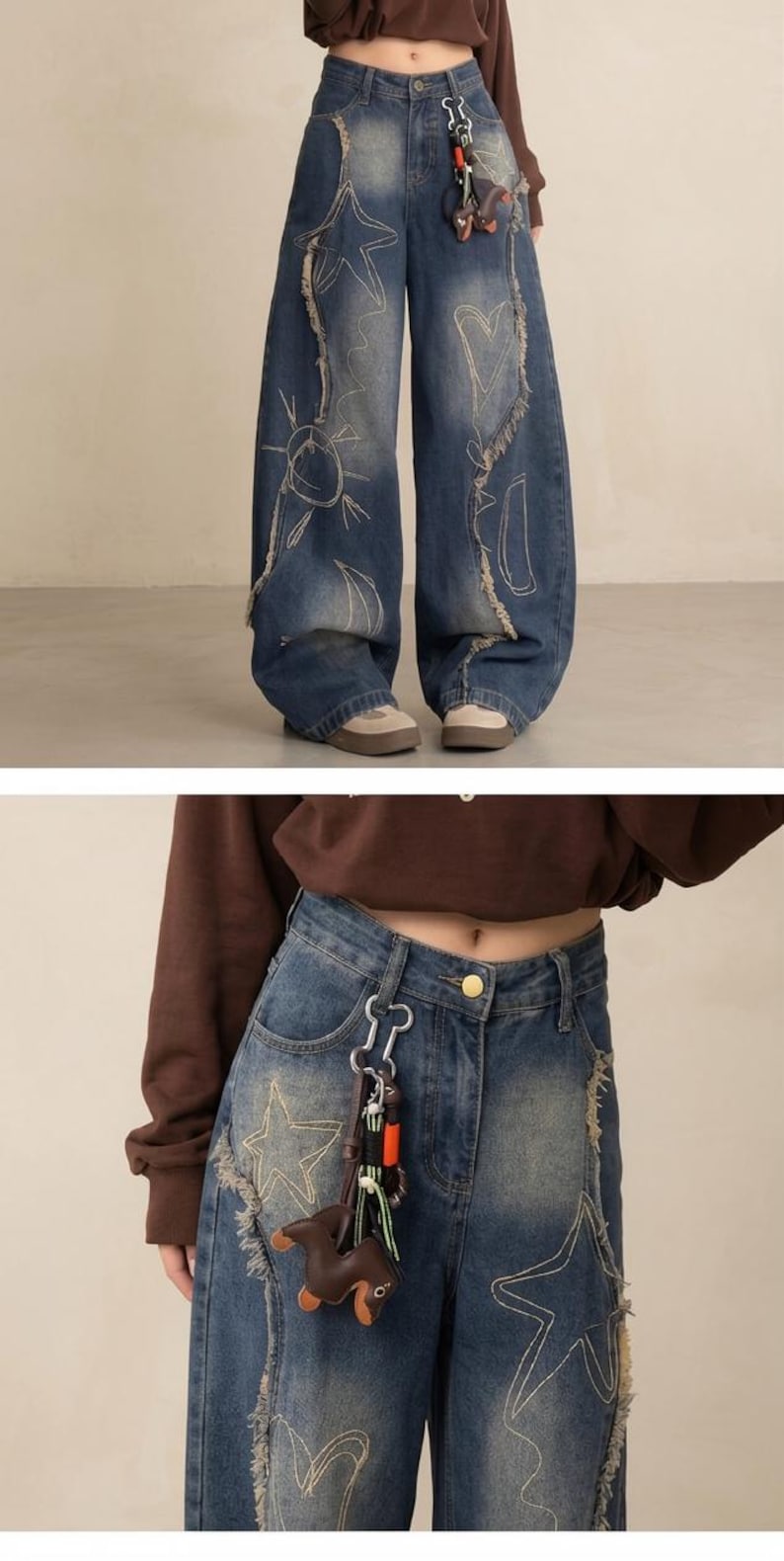 May include: Blue denim wide-leg jeans with distressed detailing and embroidered sun, star, and heart designs. Features a brown leather charm and silver keychain. The jeans have a high waist and a relaxed fit.