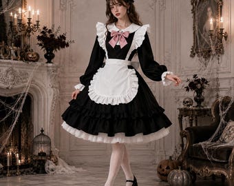 May include: A black long-sleeved dress with a white collar, a white ruffled apron, and a pink bow at the neckline. The dress features a full, layered skirt with white petticoat trim, long sleeves with ruffled cuffs, and a matching black headpiece.
