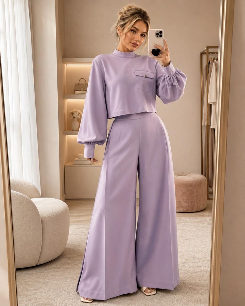 Puede incluir: Un conjunto de dos piezas en color lavanda que consta de una blusa corta de manga larga con cuello alto, un bolsillo en el pecho con bot&oacute;n y mangas voluminosas con pu&ntilde;os, combinado con pantalones de pierna ancha y cintura alta a juego.