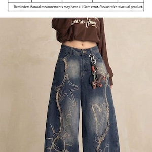 May include: Blue denim wide-leg jeans with white embroidered star and sun designs. The jeans have distressed detailing and a high waist. A size chart is visible, with measurements in centimeters, including height, weight, pants length, and waist.