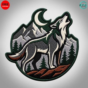 May include: An embroidered patch featuring a grey and white wolf howling at a crescent moon. The scene includes dark green pine trees, light grey mountain peaks, and a brown rocky foreground, all enclosed within a dark green circular border.