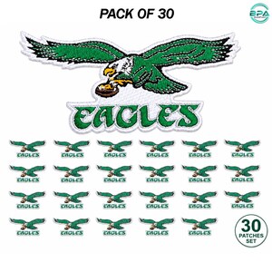 May include: A pack of 30 embroidered iron-on patches featuring a green and white eagle logo clutching a football, with the text EAGLES in green lettering below the bird. The set includes one large patch and 29 smaller identical patches.