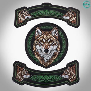 Könnte beinhalten: Ein Set aus drei bestickten Aufnähern mit Wolfsmotiven. Der mittlere runde Aufnäher zeigt einen Wolfskopf von vorne, während die beiden geschwungenen Aufnäher an den Enden Wolfsprofile aufweisen, alle mit grünen und schwarzen Akzenten.