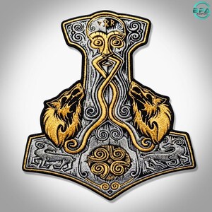 May include: An embroidered patch shaped like Mjolnir, featuring a central stylized face with gold and silver thread. Two gold wolves flank the center, with intricate silver knotwork patterns and a circular spiral design at the base on a black background.