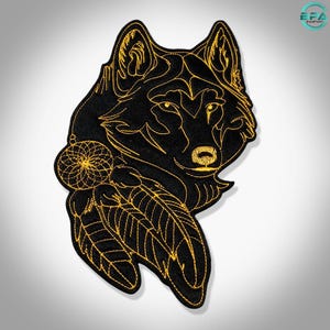 May include: An embroidered patch featuring a black wolf head outlined in gold thread. The design includes a circular dreamcatcher element hanging from the wolf's ear, adorned with two dangling feathers, all rendered in detailed gold embroidery.