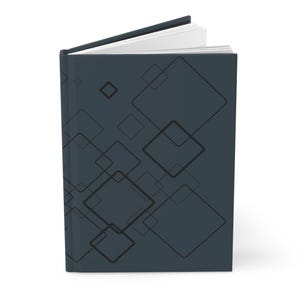 May include: A dark gray hardcover book standing upright and slightly open at the top. The front cover features a repeating pattern of thin, black outlined squares of varying sizes arranged in a scattered, overlapping geometric composition.