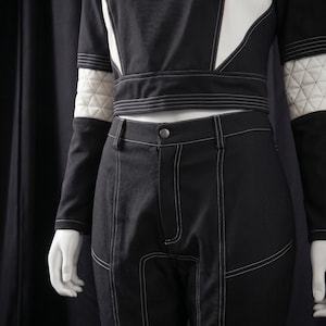 Puede incluir: Conjunto de dos piezas en blanco y negro. La parte superior tiene mangas largas con detalles acolchados blancos en la parte superior de los brazos. Los pantalones son negros con costuras blancas y paneles blancos. El conjunto se exhibe en un maniqu&iacute;.