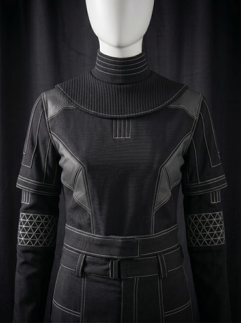 May include: Black jumpsuit with white stitching details. Features a high, ribbed collar, leather-like panels, and geometric patterns on the sleeves. The jumpsuit has a belt with a buckle.