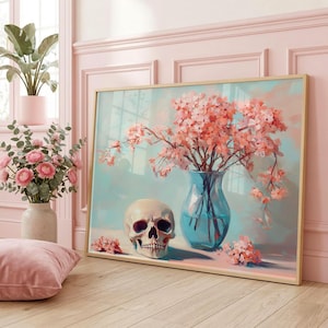 May include: A rectangular framed wall art print featuring a painting of a human skull positioned next to a blue glass vase filled with light pink cherry blossom branches, set against a soft pastel blue and pink background with scattered petals.