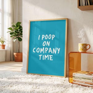 May include: A rectangular framed wall art print featuring a bright teal background with the white text I POOP ON COMPANY TIME in a casual, hand-lettered style font. The print is encased in a light-toned wooden frame and stands upright.