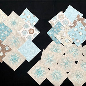 May include: A collection of fabric squares with various winter-themed patterns, including snowflakes, penguins, and a honeycomb design. The squares are in shades of blue, brown, and white.