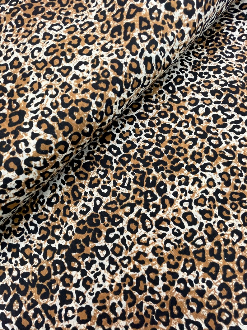 May include: Brown, black, and white leopard print fabric. The fabric has a soft, textured feel.