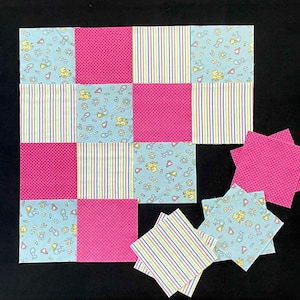 May include: A patchwork quilt with a variety of pink, blue, and white fabrics. The quilt is made up of nine squares, each with a different pattern. The squares are arranged in a grid pattern. The quilt is on a black background.