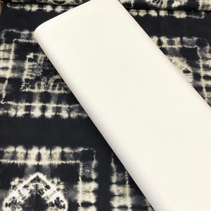 May include: A white fabric swatch laid on top of black fabric with a white and gray tie-dye pattern.