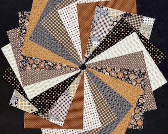 May include: A collection of square fabric swatches arranged in a circular fan pattern. The fabric pieces feature various patterns including gingham, floral prints, polka dots, and geometric designs in a color palette of brown, black, tan, and white.