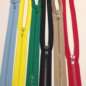 May include: Six different colors of zipper tape, including light blue, yellow, green, black, beige, and red. The zippers are all open and the slider is visible.