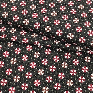 May include: Black fabric with a repeating pattern of red and white candy cane circles. The fabric has a subtle green and white geometric pattern in the background.