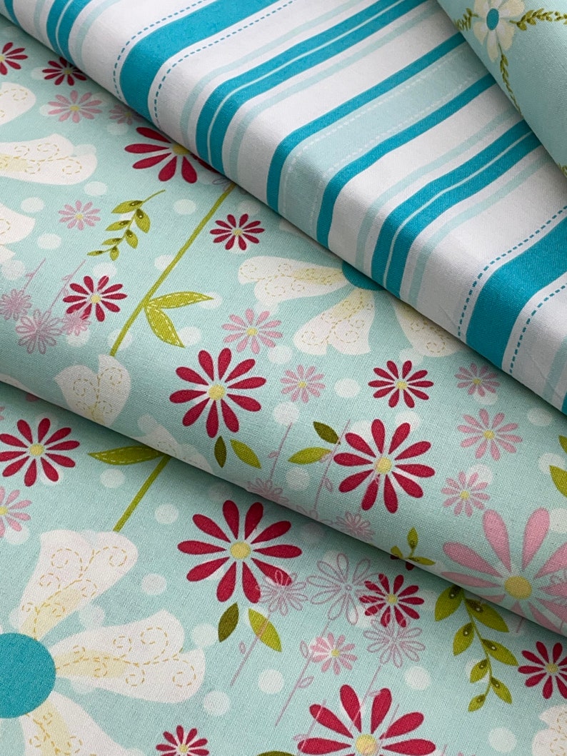 May include: Two fabric swatches, one with a blue and white striped pattern and the other with a light blue background and a floral pattern featuring red, pink, and white flowers.