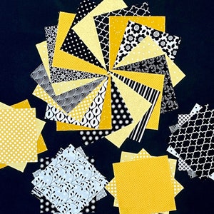 May include: A collection of 18 fabric squares in black and yellow with various patterns. The squares are arranged in a circular pattern with the yellow squares in the center and the black squares on the outside.