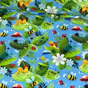 Pode incluir: Um tecido azul vibrante com um padrão caprichoso de insetos, folhas e flores. O design inclui abelhas, joaninhas, besouros e lagartas, cada um com detalhes únicos. Folhas verdes e flores brancas estão espalhadas pelo tecido.