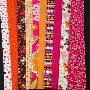 May include: Assortment of 10 fabric strips in various pink, orange, and brown patterns. The strips feature butterflies, polka dots, and floral designs.