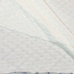 May include: White fabric with a textured, wavy pattern. The fabric is folded in half, showing the pattern on both sides.