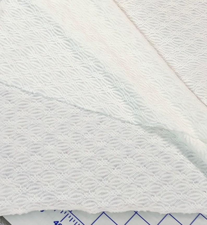 May include: White fabric with a textured, wavy pattern. The fabric is folded in half, showing the pattern on both sides.