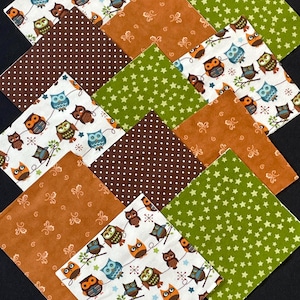 Puede incluir: Diez cuadrados de tela con diferentes patrones de búhos. Los patrones incluyen búhos en ramas, búhos con estrellas y búhos con lunares. Las telas son en tonos de marrón, verde y blanco.