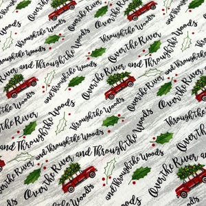 May include: White fabric with a repeating pattern of red trucks carrying Christmas trees, green holly leaves, and the text "Over the River and Through the Woods" in black script. The background has a subtle, textured gray wash.