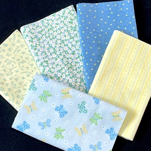 May include: Five fabric swatches in various patterns and colors. The swatches are light blue, yellow, and green. The patterns include butterflies, polka dots, and floral designs.
