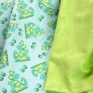 May include: Two pieces of fabric, one with a light blue background and a repeating pattern of green dragons, the other a solid green with white polka dots.