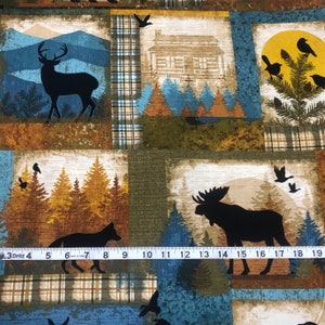 May include: Fabric with a patchwork design featuring woodland scenes. Each square showcases a different image: a deer, a cabin, birds, a fox, and a moose. The color palette includes shades of blue, brown, and green.
