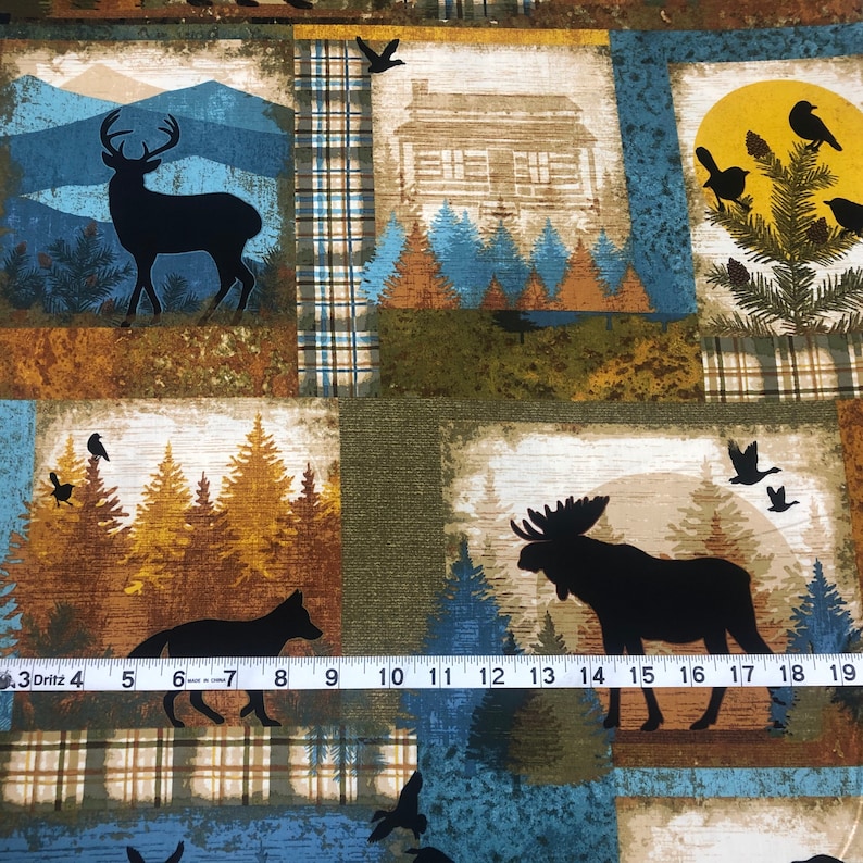 May include: Fabric with a patchwork design featuring woodland scenes. Each square showcases a different image: a deer, a cabin, birds, a fox, and a moose. The color palette includes shades of blue, brown, and green.