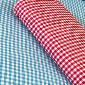 May include: Red and blue gingham fabric. The red gingham fabric is folded on top of the blue gingham fabric.