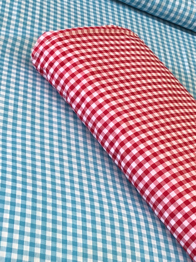 May include: Red and blue gingham fabric. The red gingham fabric is folded on top of the blue gingham fabric.