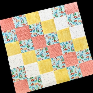 May include: A patchwork quilt with a yellow, white, and pink color scheme. The quilt is made of squares with a variety of patterns, including polka dots, stripes, and a mermaid print.