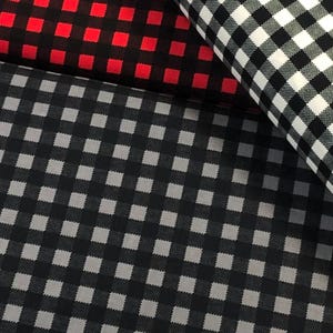 May include: Black and white gingham fabric with a smaller black and gray gingham fabric underneath. Both fabrics have a checkered pattern.