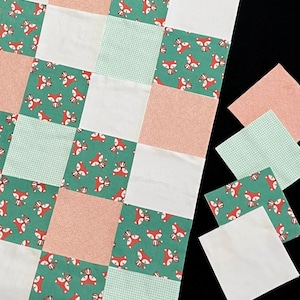 May include: A patchwork quilt with a green, white, and pink checkered pattern. The quilt is made up of squares with different designs, including foxes, flowers, and geometric shapes.