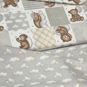 May include: A fabric featuring a patchwork design of brown teddy bears, white clouds, stars, and beige plaid patterns. One square displays the text Love you Beary much. A second layer of fabric shows a repeating pattern of white clouds on a grey background.